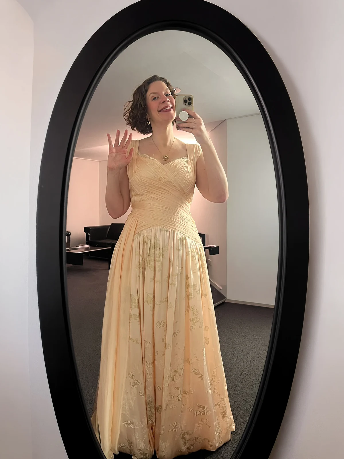 Catriona Morison zeigt ihr FRILISA Kleid im Spiegel: drapiertes Oberteil und goldene Ornamente im Rock