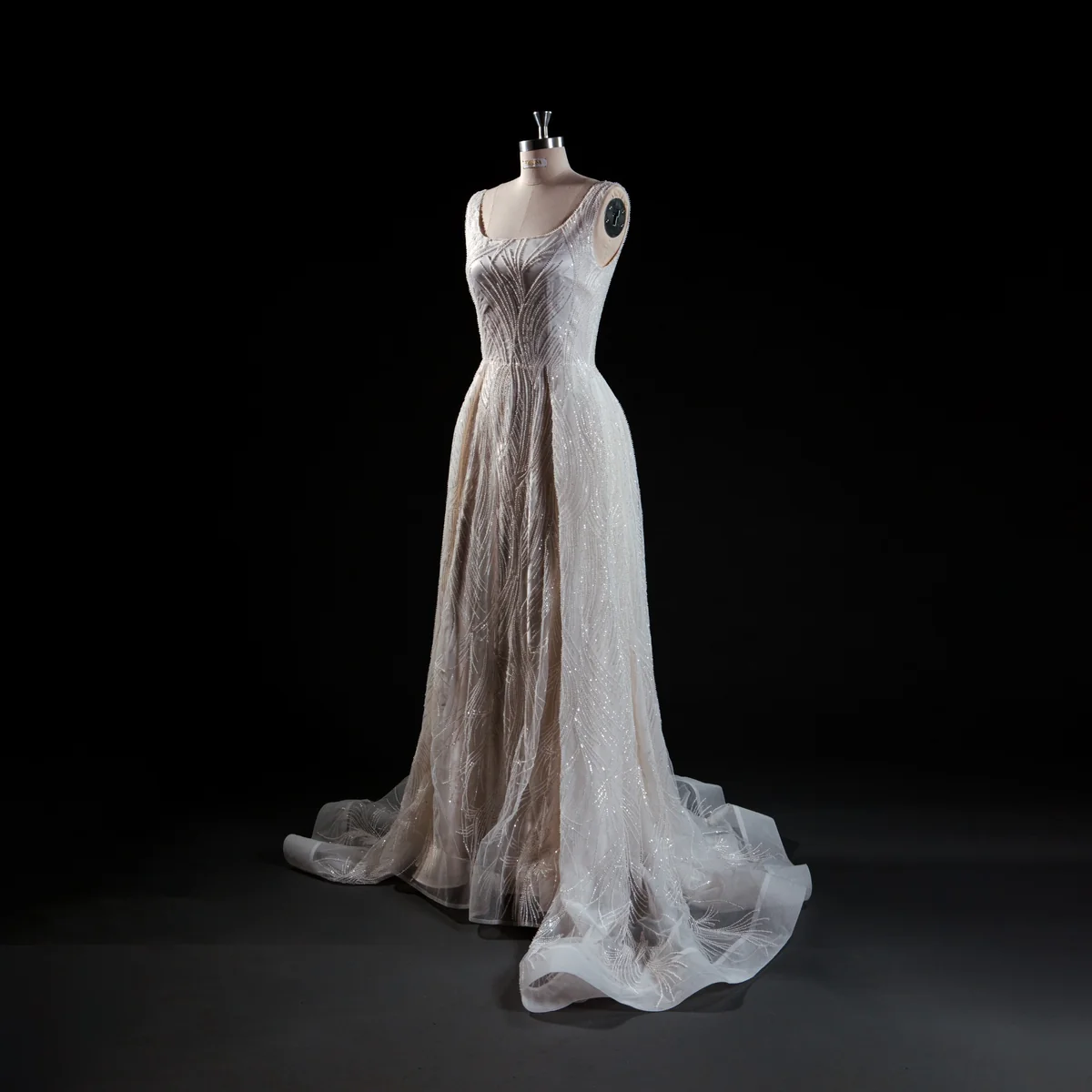 Draped wedding dress with slender straps and a train on a dress form