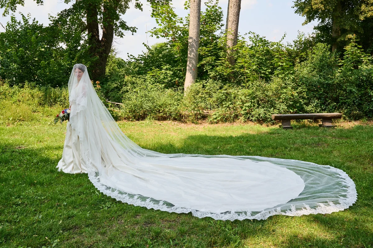 Bride with a long trailing veil on a garden lawn