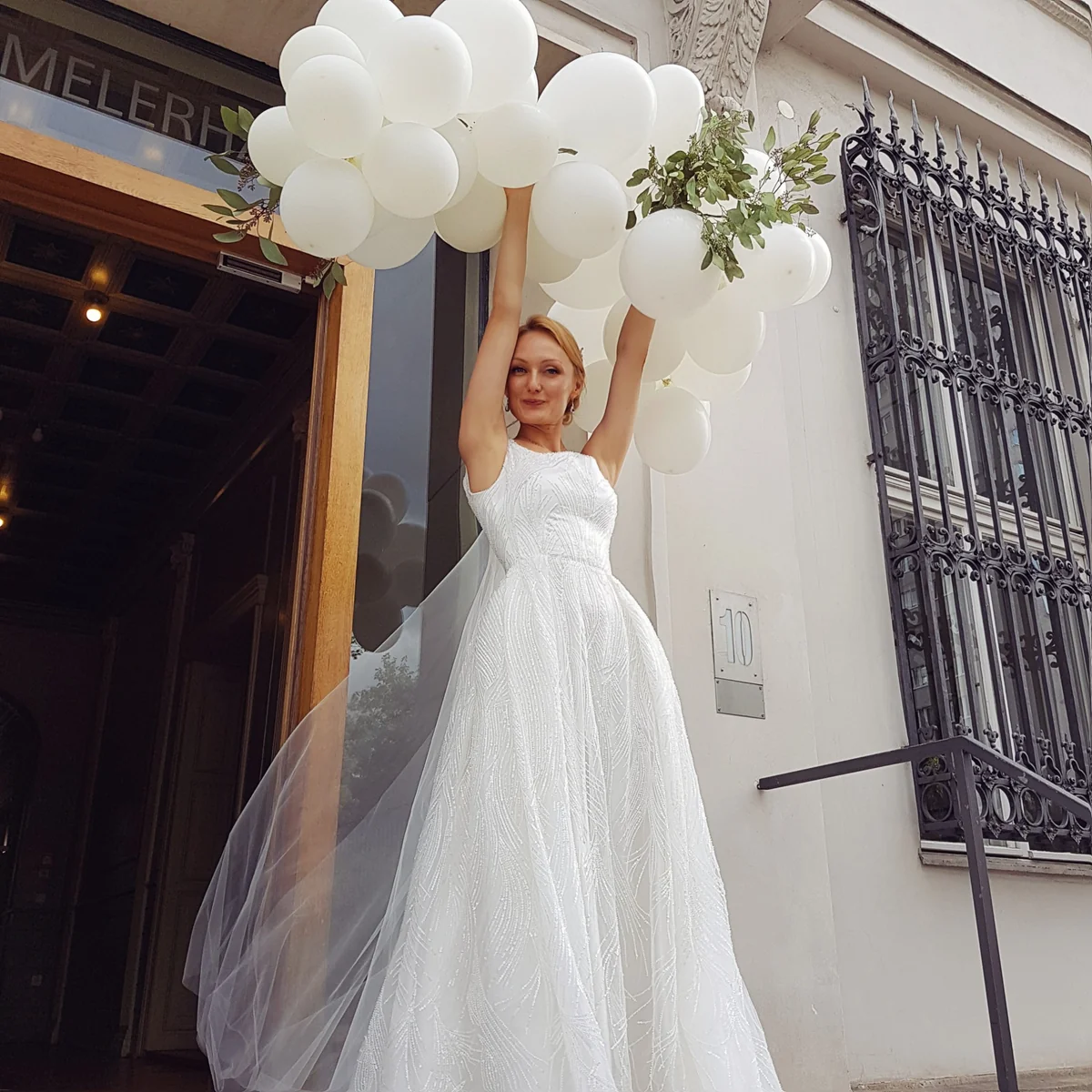Bride in a white wedding dress holding white balloons