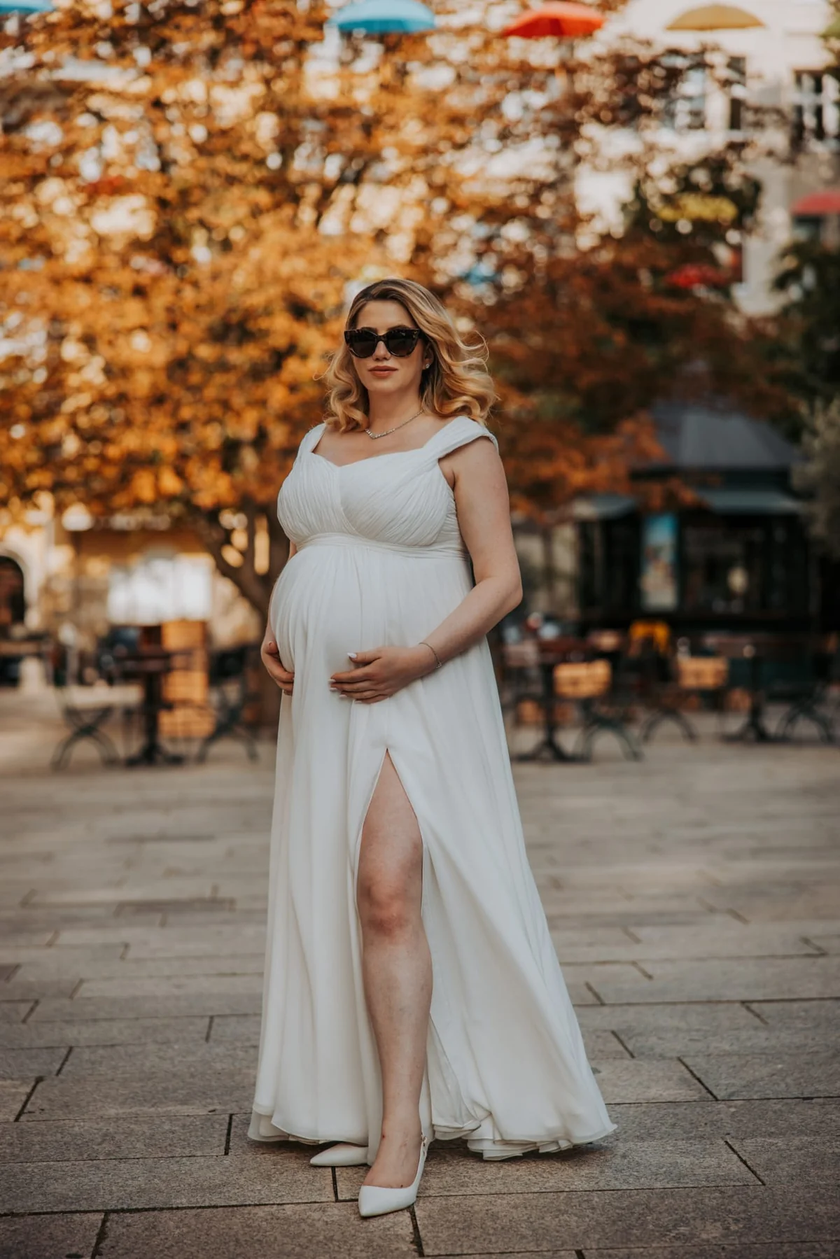 Bride in a white wedding dress with a side slit against autumn trees