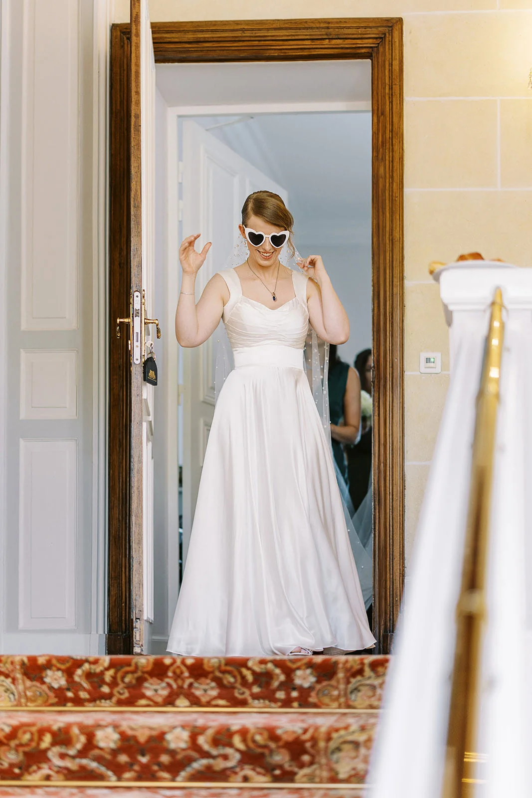 Bride in a white wedding dress and sunglasses beside a mirror