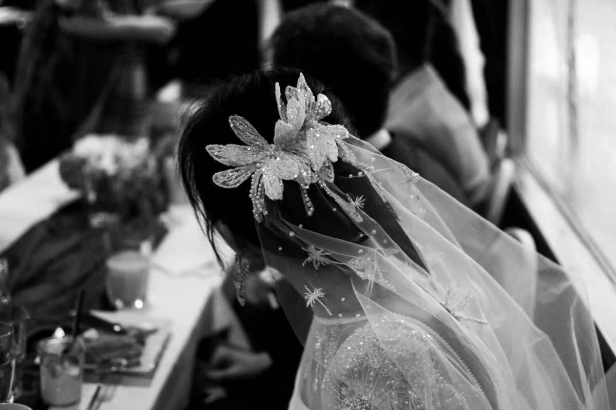 Black-and-white photograph of a bridal veil and floral hair detail