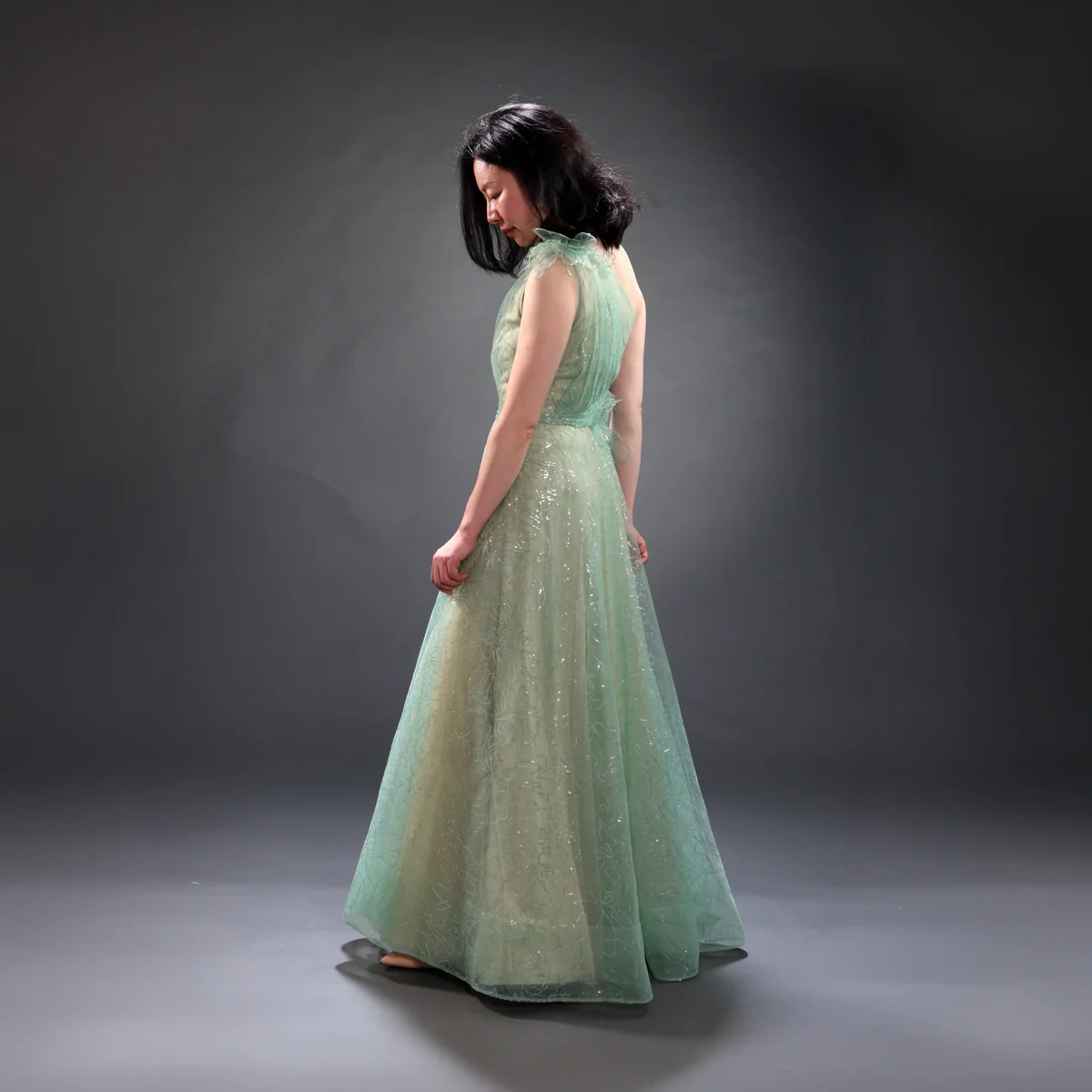 Model in einem mintgrünen Abendkleid mit besticktem Oberteil in seitlicher Ansicht