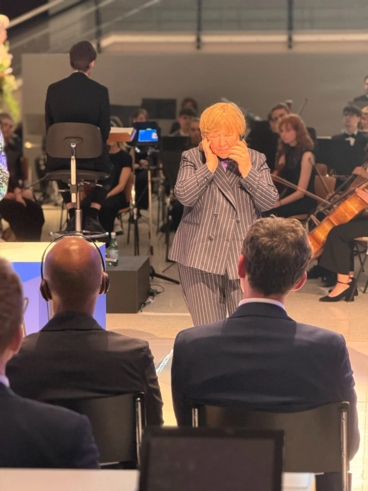 Swetlana Alexijewitsch trägt ihren FRILISA Nadelstreifenanzug bei einem öffentlichen Auftritt vor einem Orchester